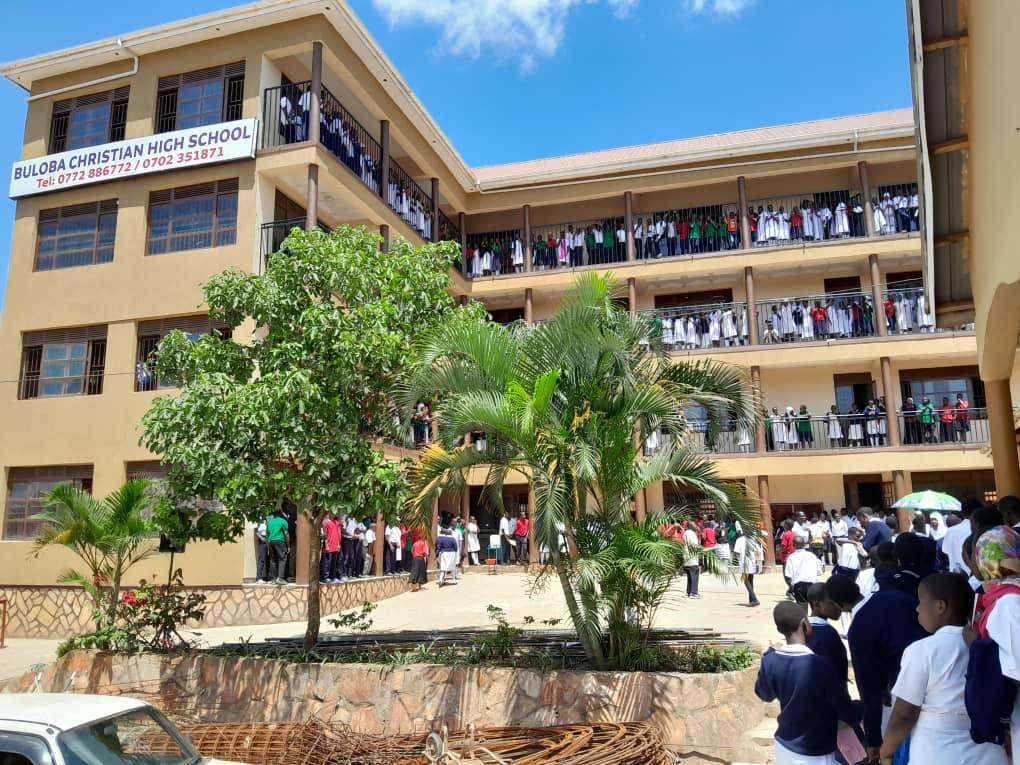 The main classroom block of Buloba Christian High School, students gathered on every balcony beneath the school signboard